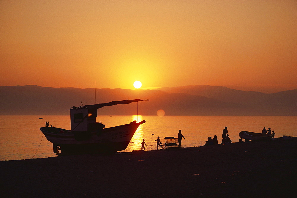 People and trawler at sunset on the beach of the village El Cabo de Gata, Almeria province, Andalusia, Spain