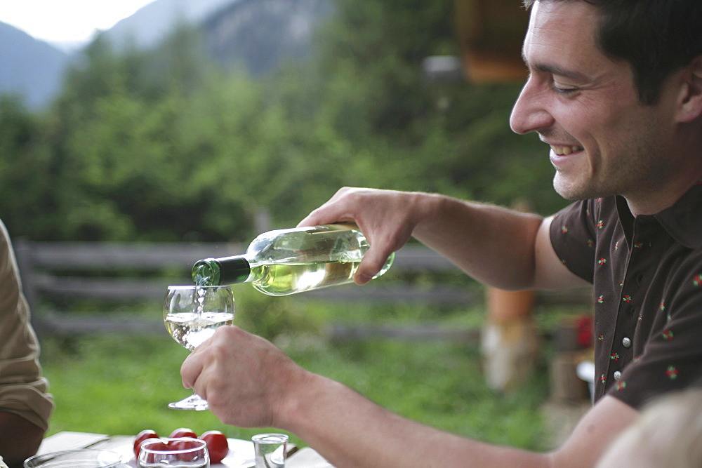 Man pouring wine into glass, National Park Hohe tauern, Kaernten, Austria