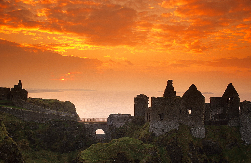 The ruins of Dunluce Castle on shore in the afterglow, County Antrim, Ireland, Europe