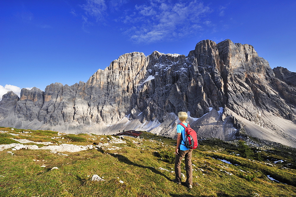 Woman walking towards Rifugio Tissi, Civetta in the background, Civetta, Dolomites, UNESCO World Heritage Site, South Tyrol, Italy