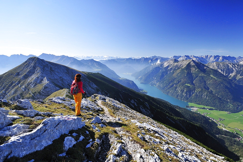 Woman walking at Unnutz with view to lake Achensee, Rofan mountain range and Alpine main ridge, Unnutz, Unnuetz, Rofan, Tyrol, Austria