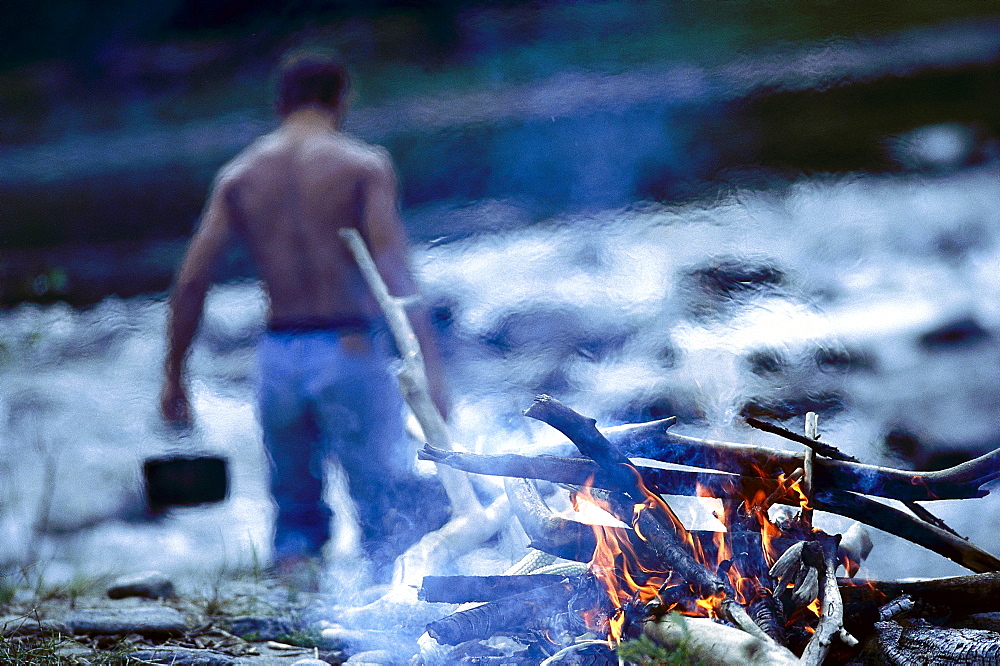 Campfire, topless man in background, riverside of Isar, Upper Bavaria, Germany