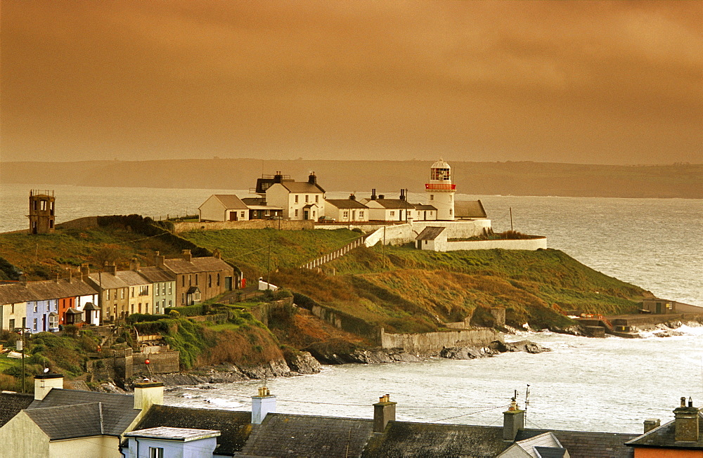 Houses and lighthouse on shore in the evening, Roche's Point, County Cork, Ireland, Europe