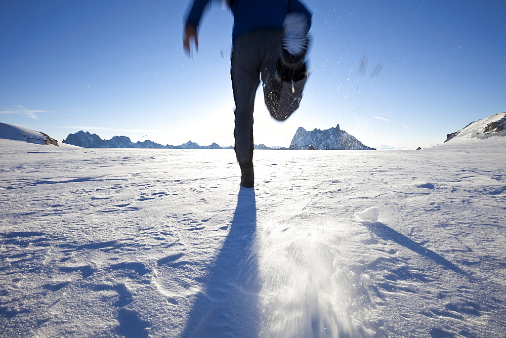 Man running over glacier towards sunrise, overlooking Les Grandes Jorasses and Dent du Geant, Chamonix Mont Blanc, France, Europe