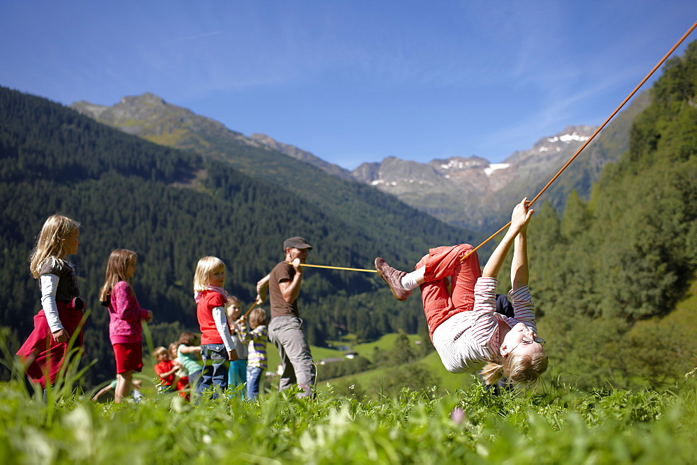 Girl making her way hand over hand along a rope, Gossensass, Brenner, South Tyrol, Trentino-Alto Adige/Suedtirol, Italy