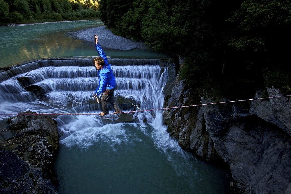 Young man balancing on a highline over a stream, Fuessen, Bayern, Deutschland, Europe