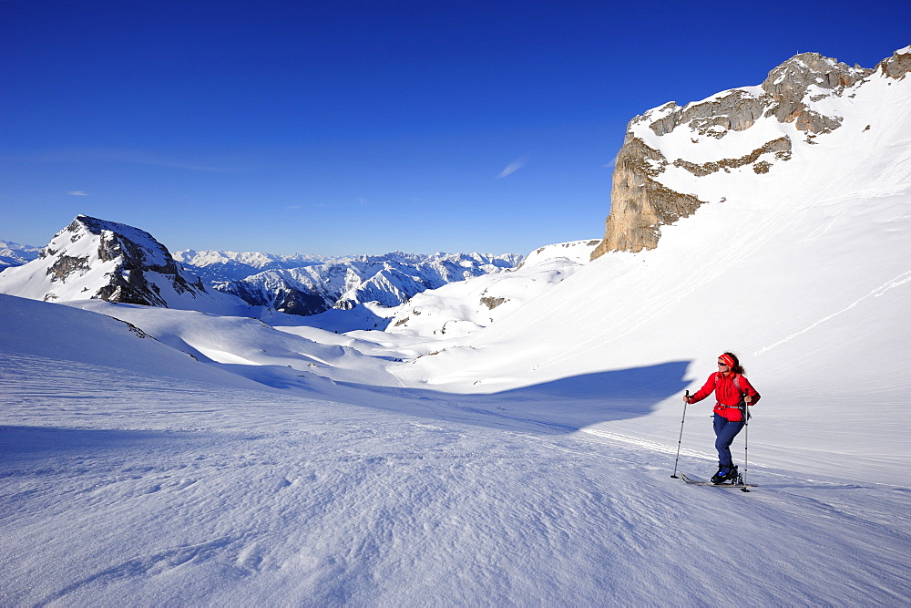 Woman with crosscountry skis ascending to Rofanspitze, Karwendel range in the background, Rofanspitze, Rofan, Tyrol, Austria, Europe