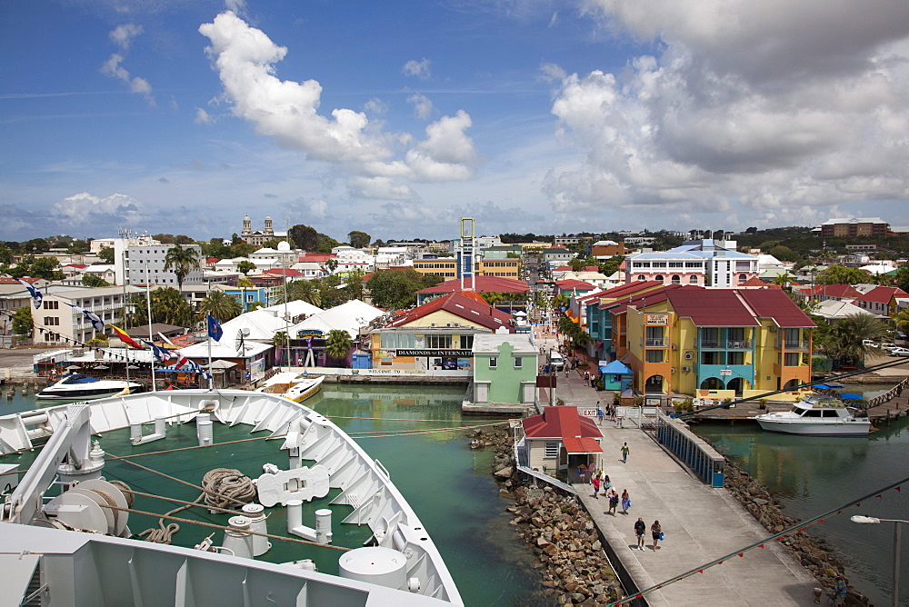 Bow of cruise ship MS Deutschland (Reederei Peter Deilmann) at a pier with colorful houses and shops near the port, St. John's, St. John, Antigua, Antigua and Barbuda, Caribbean