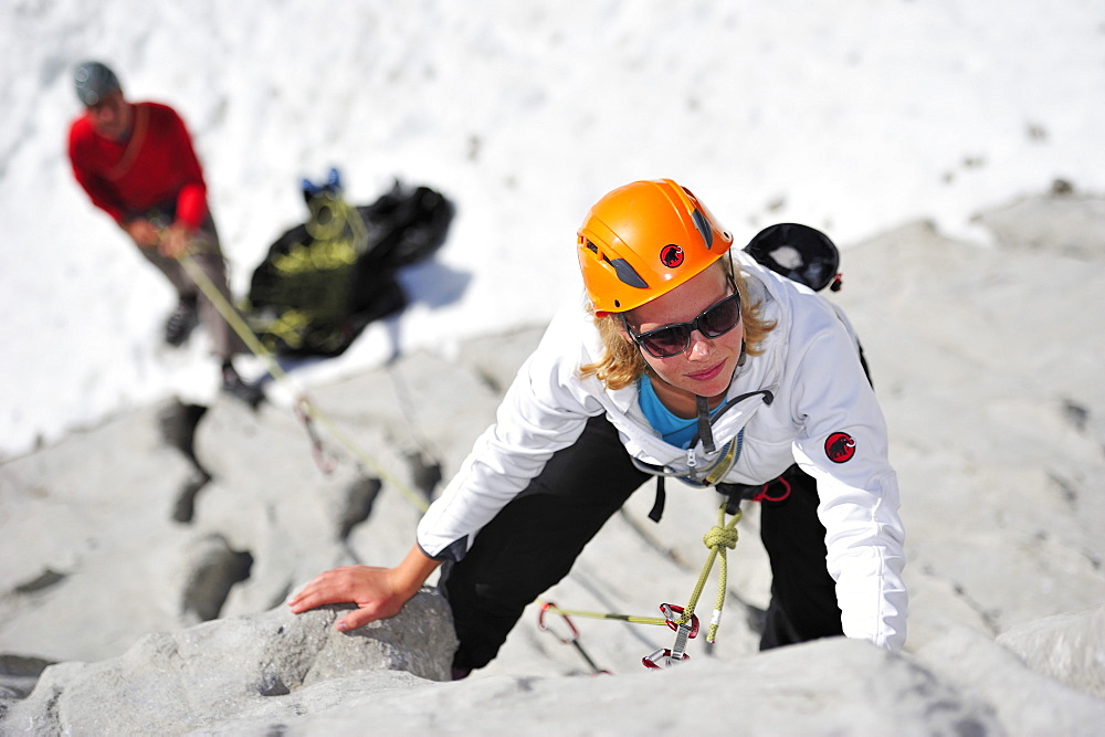 Young woman climbing while young man belaying, Multerkarwand, Treffauer, Wegscheidalm, Wilder Kaiser, Kaiser Mountain Range, Tyrol, Austria