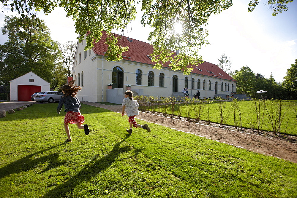 Children running over a meadow near a hotel, Fincken, Mecklenburg-Western Pomerania, Germany