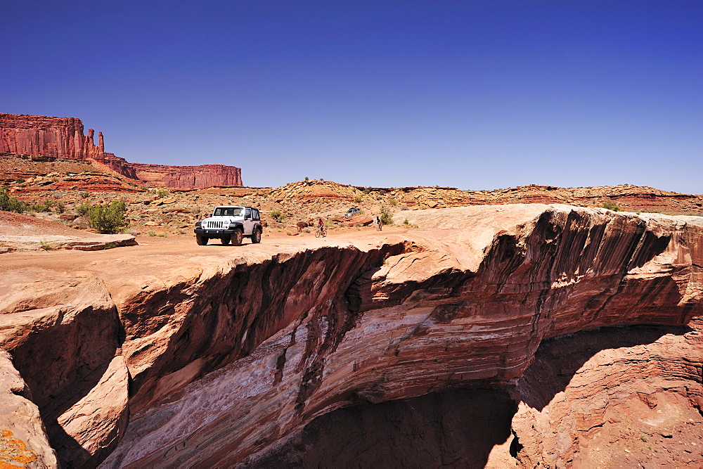 Jeep driving at brim above Colorado River, White Rim Drive, White Rim Trail, Island in the Sky, Canyonlands National Park, Moab, Utah, Southwest, USA, America