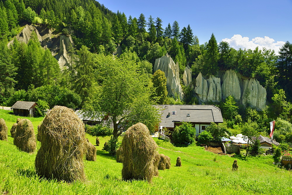 Hay stacks with restaurant and earth pyramids of Terenten in the background, Terenten, Puster valley, South Tyrol, Italy