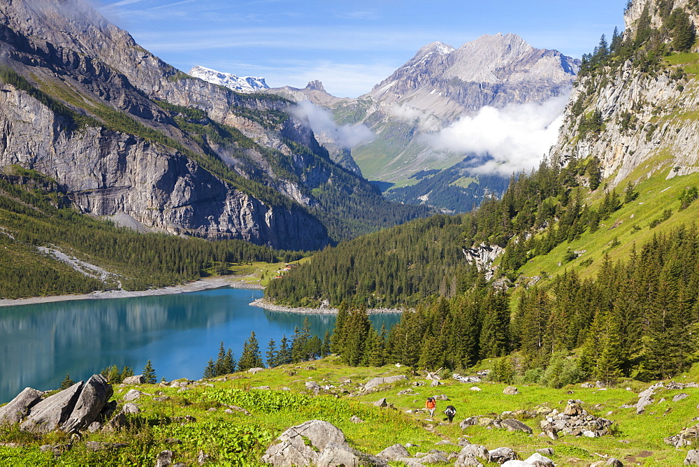 A man and a woman hiking above lake Oeschinen, Alp Unterbaergli, view to Wildstrubel, Bernese Oberland, Canton of Bern, Switzerland