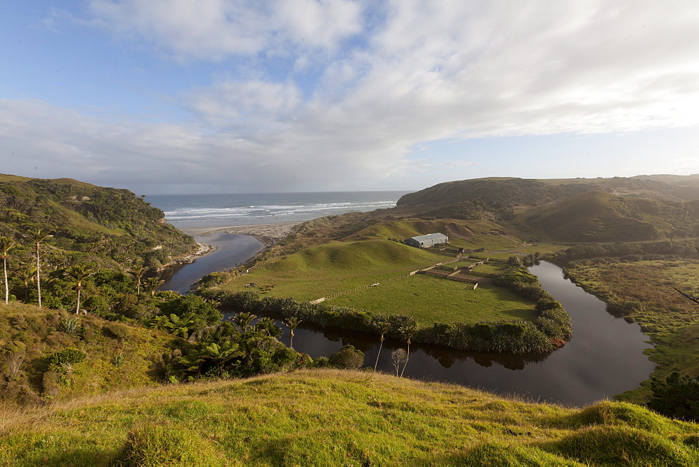 Farmland on the Anatori River estuary, pastures surrounded by arm of the river and coastline, west coast of South Island, New Zealand