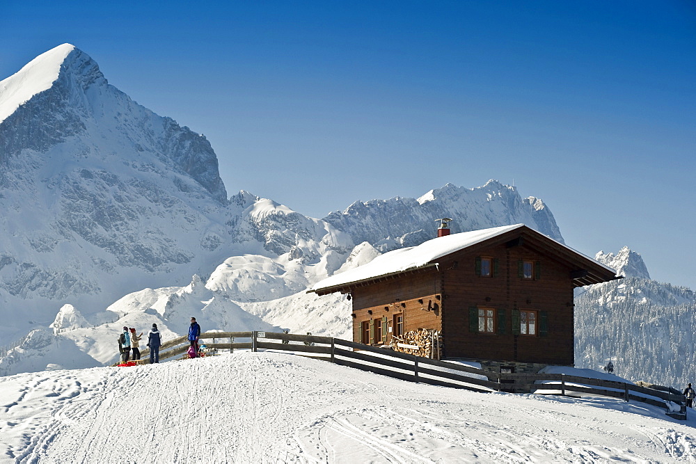 People sledging at Eckbauer, Alpspitze and Zugspitze in the background, Garmisch-Partenkirchen, Bavaria, Germany