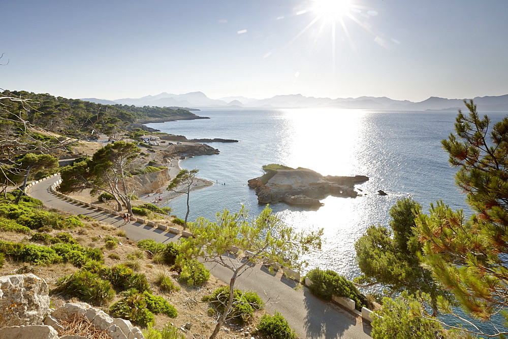 Coastal road leads to S'Illot chapel, view over Playa S'Illot beach, Alcudia peninsula, bay of Pollenca, Mallorca, Balearic Islands, Spain