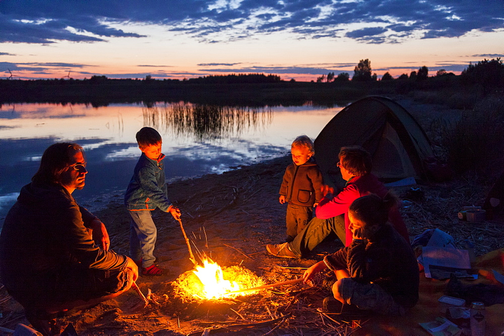 Family at campfire, Werbeliner See, Saxony, Germany