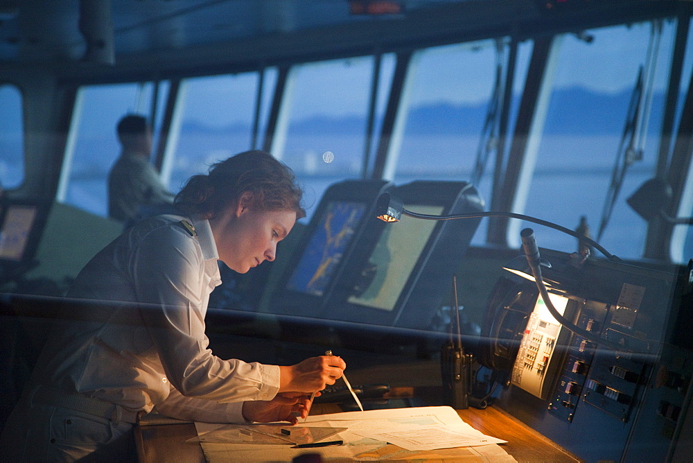 Safety Officer Claudia Kempkes charting course on bridge of cruise ship MS Deutschland (Reederei Peter Deilmann) at dawn, Puerto Vallarta, Jalisco, Mexico