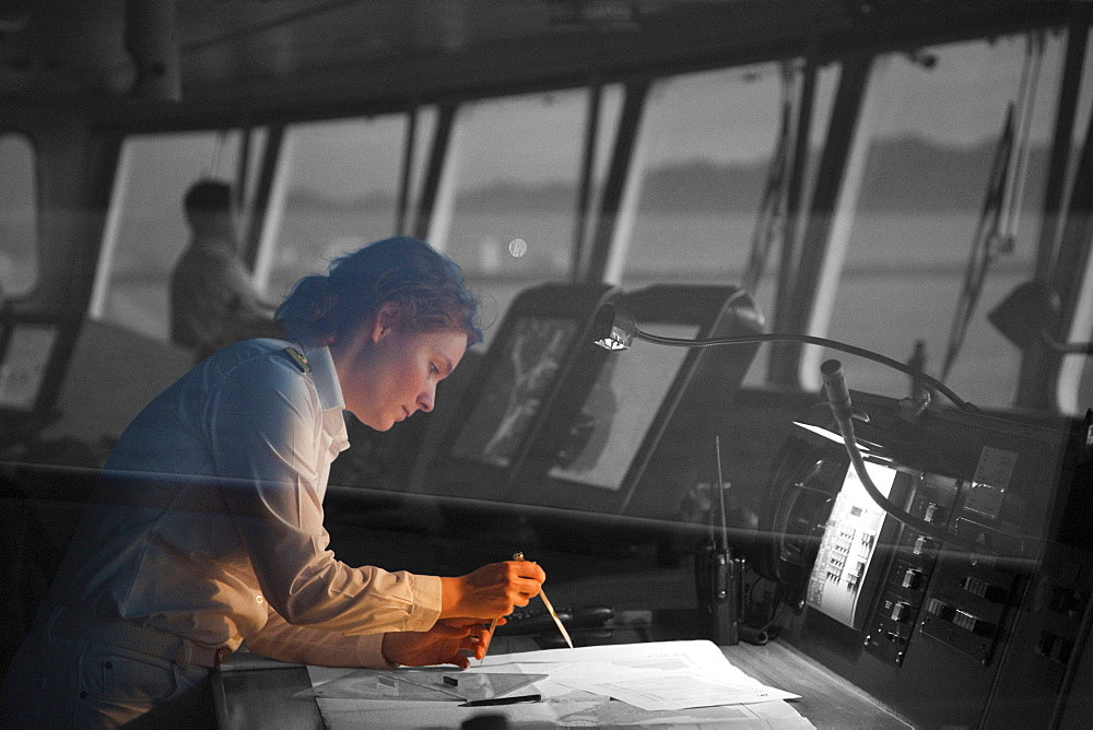 Safety Officer Claudia Kempkes charting course on bridge of cruise ship MS Deutschland (Reederei Peter Deilmann) at dawn, Puerto Vallarta, Jalisco, Mexico