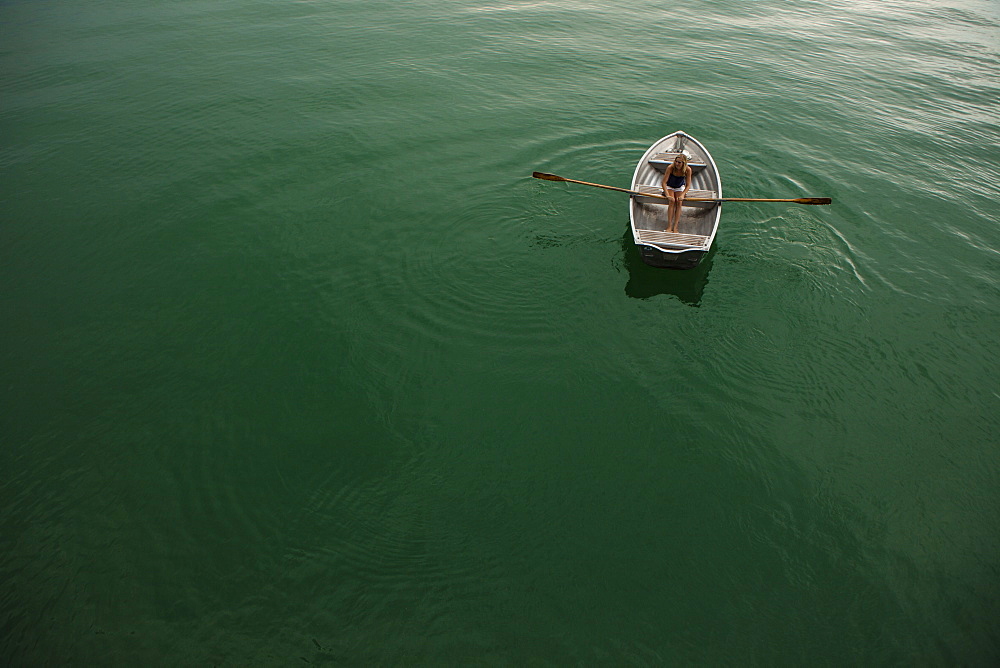 Young woman in a rowboat on lake Starnberg, Bavaria, Germany