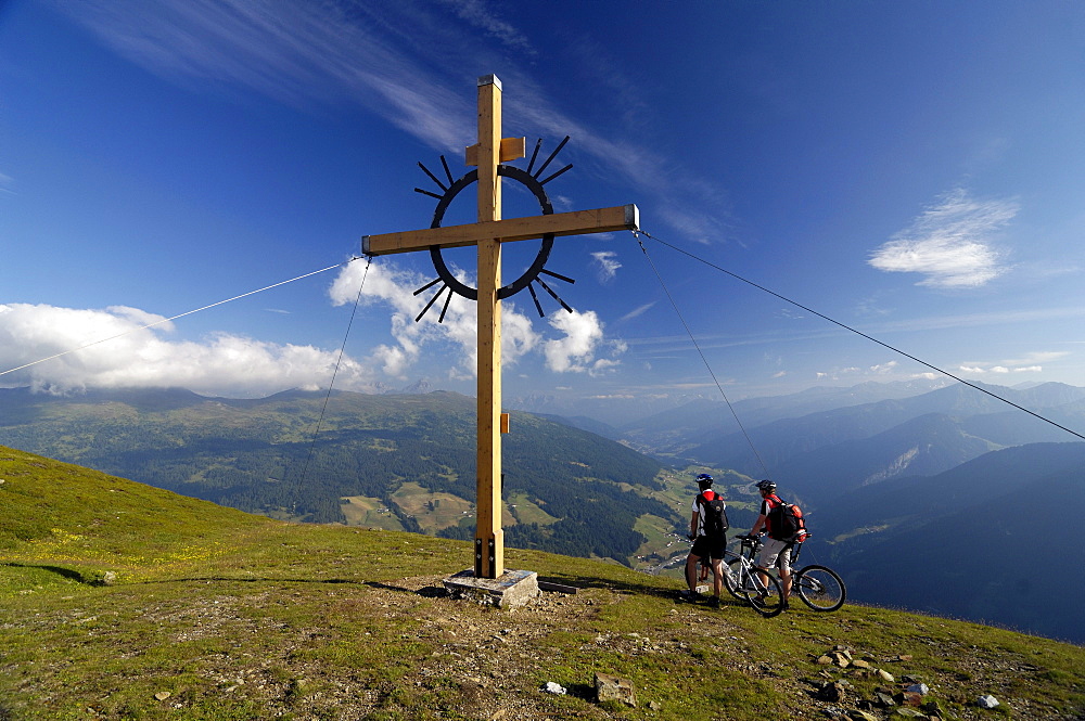 Two people on a mountain bike tour at the summit cross, Sattelberg, Brenner, Tyrol, Austria