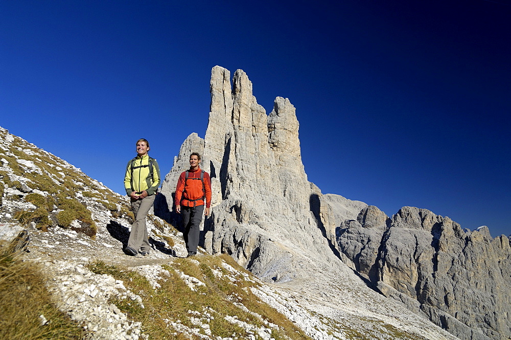 Couple hiking in the mountains, Vajolet towers in the background, Rosengarten, Dolomites, Trento, South Tyrol, Italy