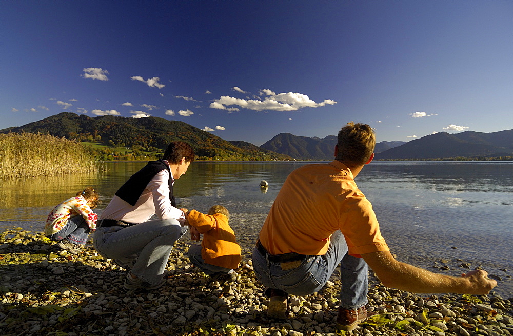 Family hiking at Lake Tegernsee, throwing stones into the water, Upper Bavaria, Bavaria, Germany, Europe