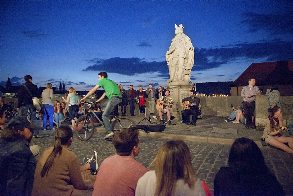 Evening mood with street artists and young people on the old Main bridge, Wuerzburg, Franconia, Bavaria, Germany