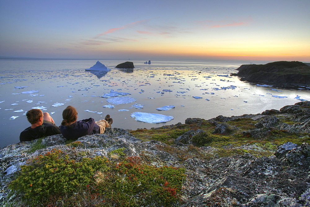 Couple looking out at an Iceberg at Sunset, Twillingate, Newfoundland