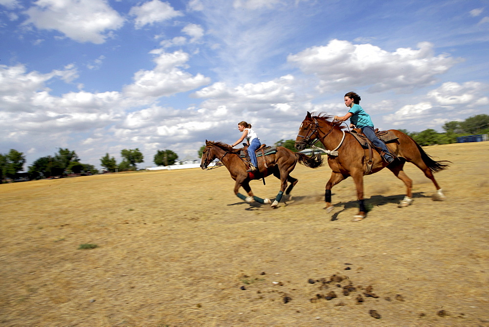 Galloping past at full speed on horses, Val Marie, Saskatchewan.