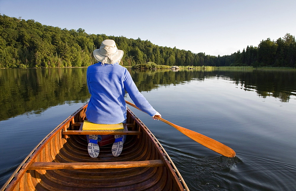 Woman paddling canoe on Smoke Lake, Algonquin Park, Ontario