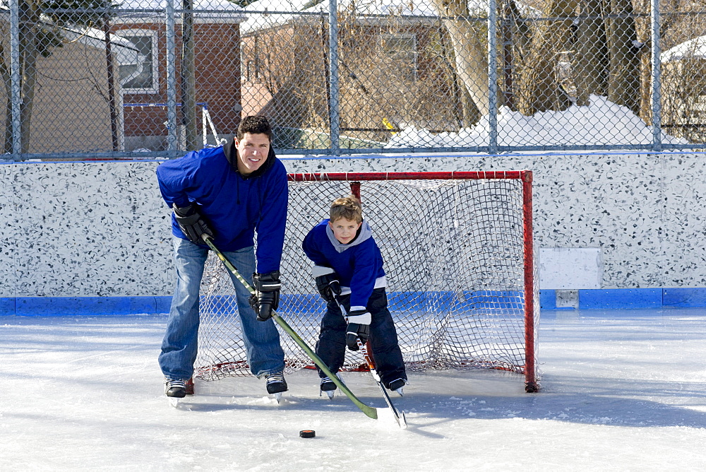 Father and son hockey players on an outdoor rink, Toronto, Ontario