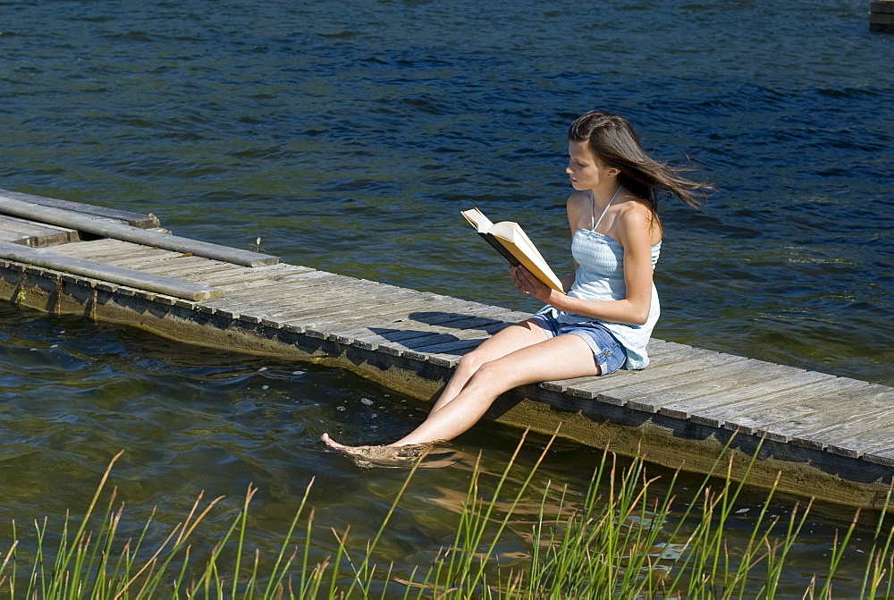 Teenager reading on a dock, Shawnigan Lake, Victoria, British Columbia