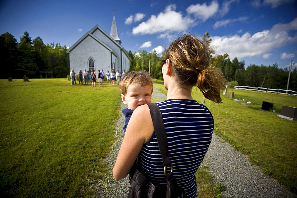 Mother carrying her young boy towards a small Catholic church in Merland, Antigonish County, Nova Scotia