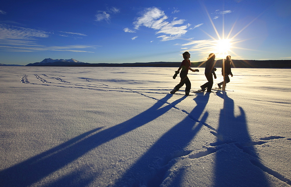 Snowshoers in bright winter sun on the frozen Teslin Lake, Yukon