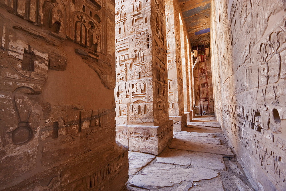 Bas-reliefs with original colors on the walls and columns of a portico of the first courtyard of the Mortuary Temple of Ramses III, Medinat Habu, Luxor, Qina, Egypt