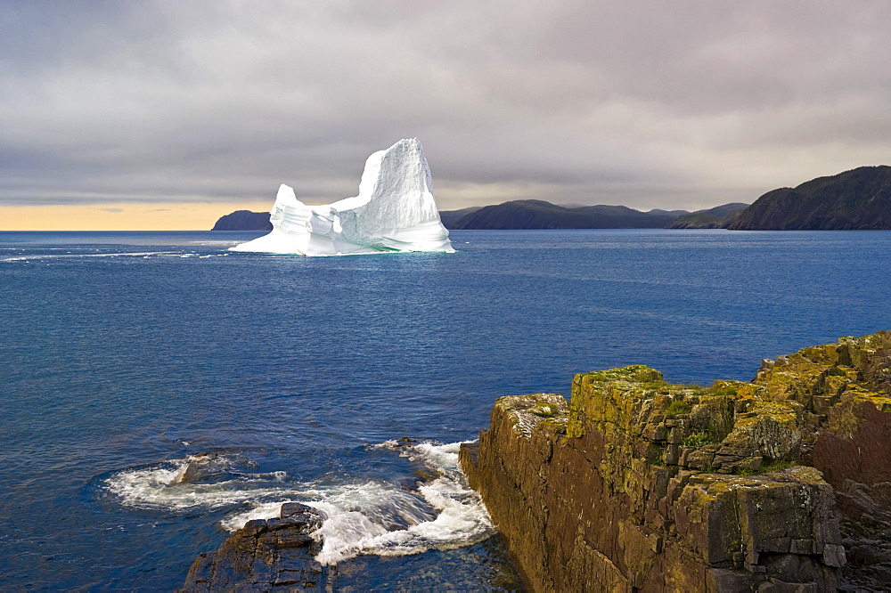 Iceberg floats in Trinity Bay off the Bonavista Peninsula with Rocky Shoreline, Eastern Newfoundland