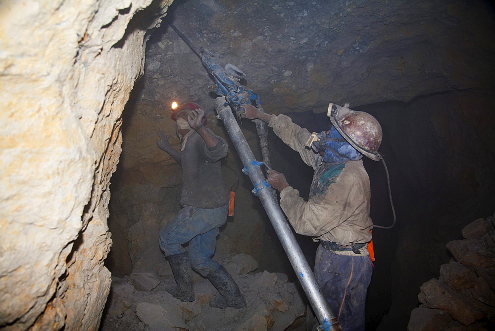 Miners drilling holes to place dynamite into the rock with a compressed air pneumatic drills in a shaft of the Cerro Rico de Potosi mine, Potosi Department, Bolivia