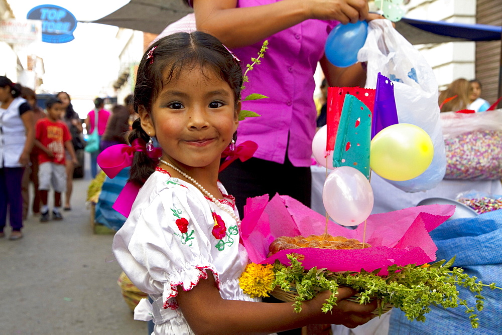 Girl carrying a gift basket at the Jueves de Comadres market during Carnaval Chapaco, Tarija, Bolivia