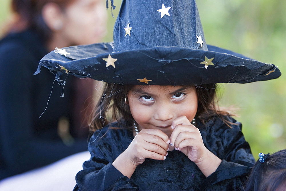 Girl dressed in a Halloween costume for the celebration of Dia de los Muertos, the Day of the Dead at the new Erongaricuaro cemetery. People decorate the graves of their loved ones with offerings of flowers, particularly marigolds (cempoalxochitl or zempasuchil), bread of the dead (pan de muerto), candles, the deceased's favourite food, drinks and personal belongings to guide their spirits home. Families celebrate their late relatives by the tombs on November 2, All Souls Day., Michoacun, Mexico