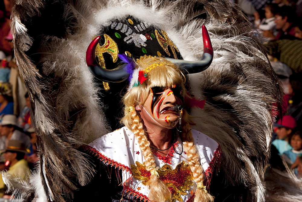 Tobas dancer wearing an elaborate mask, feather headdress and costume in the procession of the Carnaval de Oruro, Oruro, Bolivia