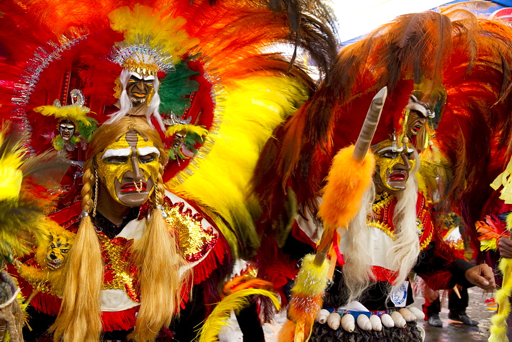 Tobas dancers wearing elaborate masks, feather headdresses and costumes in the procession of the Carnaval de Oruro, Oruro, Bolivia