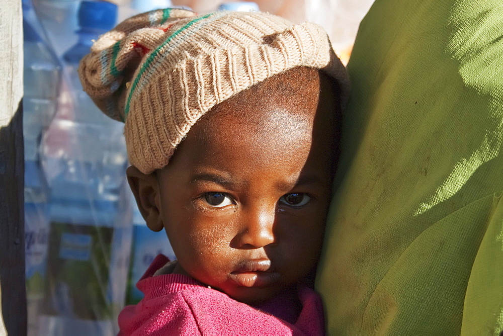 Scared young boy gets closer to his mother in Ranohira, Fianarantsoa Province, Madagascar