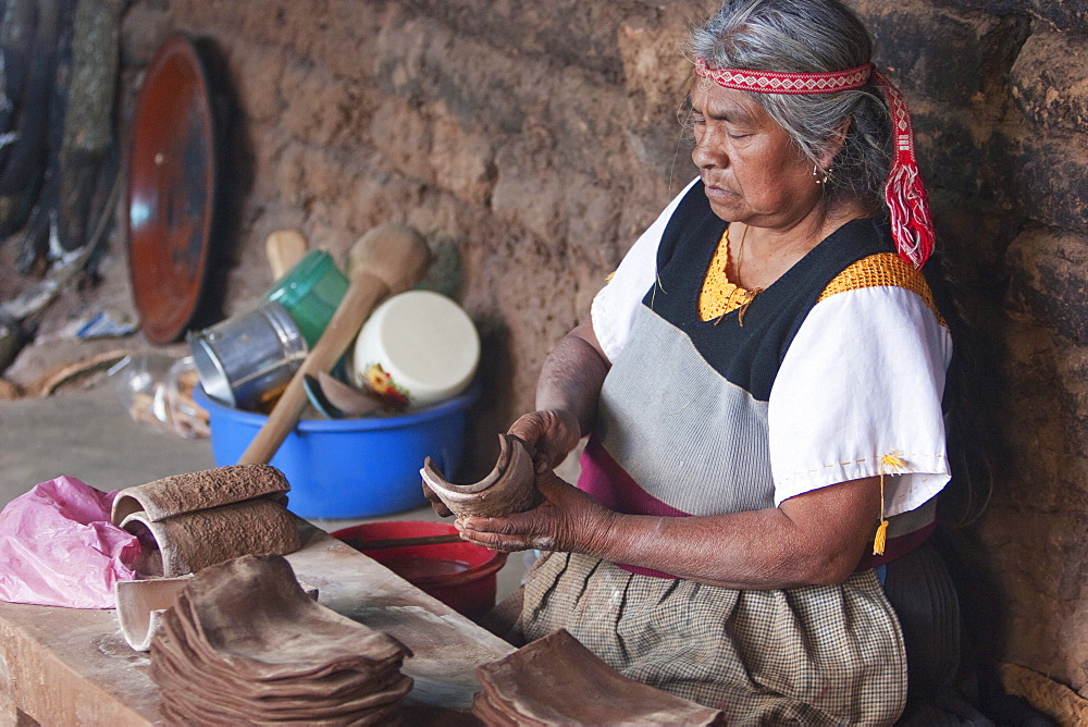 Old Purupecha woman making pottery candle stick holders, Santa Fu de la Laguna, Michoacun, Mexico