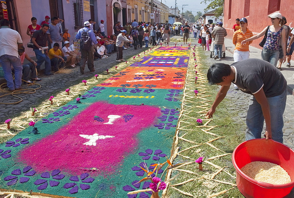 People making a carpet made of sand & sawdust along the Good Friday processional route. Carpet-making is thought of as a sacrificial act, as the elaborate detail and time that go into the carpet making is a way for people to give something of themselves in memory of the crucifixion of Jesus. These carpets last on average 2 hours before they are destroyed by the many feet that march over them during a procession in Antigua Guatemala., Sacatepuquez, Guatemala