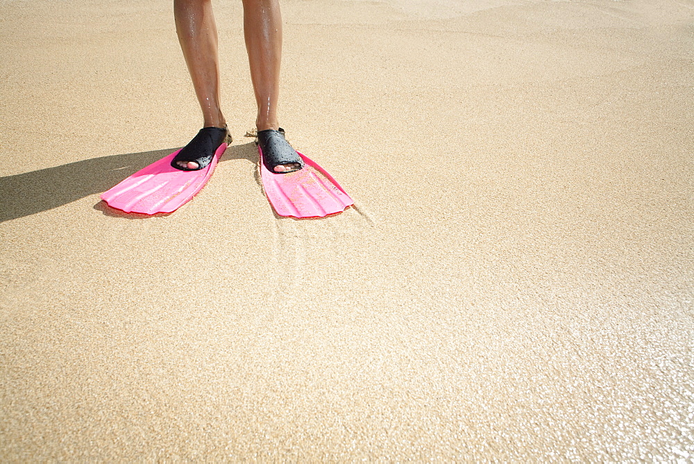 Hawaii, Woman wearing pink snorkel flippers on sandy beach.