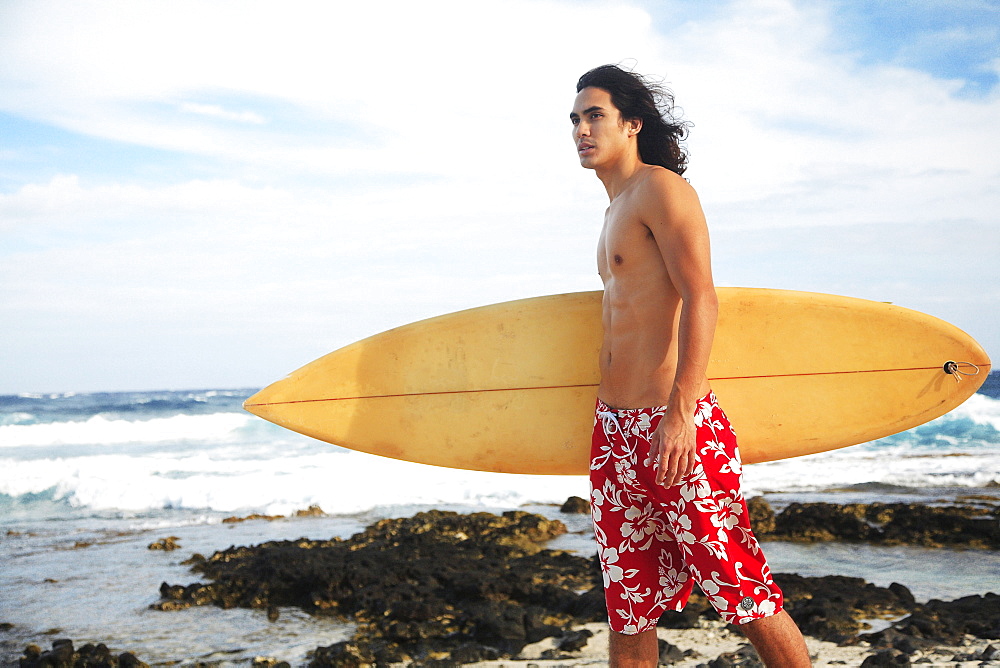 Hawaii, Oahu, young man at the beach with surfboard.