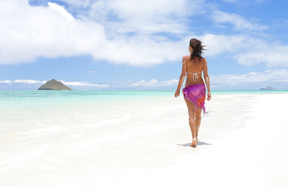 Hawaii, Oahu, Lanikai Beach, Woman walking along sandy shore.