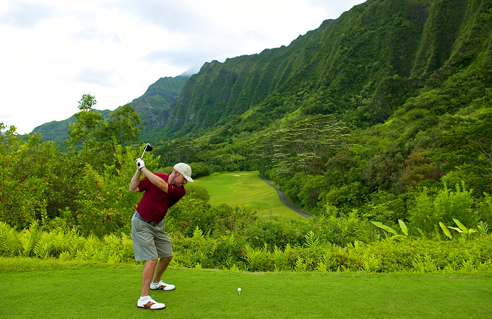 Hawaii, Oahu, Honolulu, Ko'olau Golf Course, Man driving on the 15th hole with beautiful mountain view.