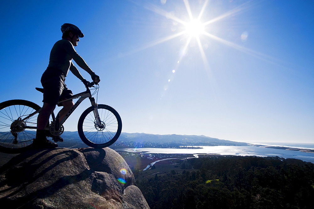 California, Morro Bay State Park, Man on bicycle looks over Morro Bay from cliff.